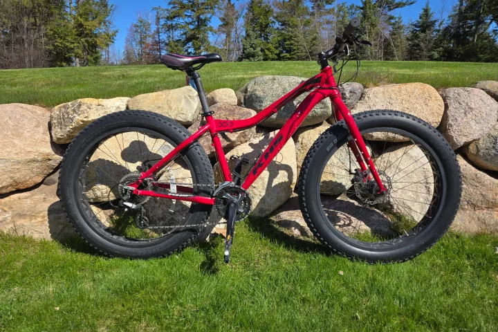 a bicycle parked on the side of a dirt field
