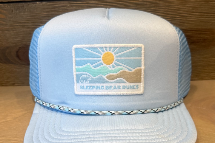 Blue trucker hat with Sleeping Bear Dunes patch, sun, and waves design.
