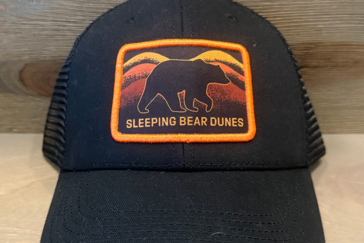 Black cap with Sleeping Bear Dunes bear patch in orange and red.