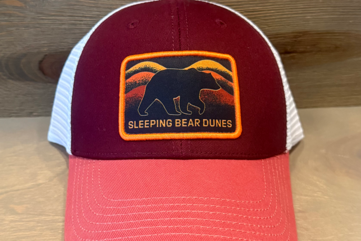 Trucker hat with red front and white mesh, logo of a bear and 'Sleeping Bear Dunes' text.