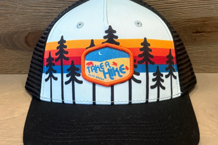Trucker hat with colorful pine tree pattern and 'Take a Hike' patch.